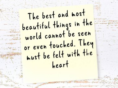 Tahta duvarda el yazısı motivasyon alıntısı olan sarı yapışkan not