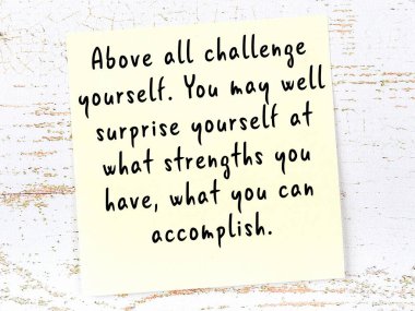 Tahta duvarda el yazısı motivasyon alıntısı olan sarı yapışkan not