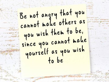 Sarı yapışkan not, ahşap duvarda el yazısıyla yazılmış zekice bir alıntıyla.