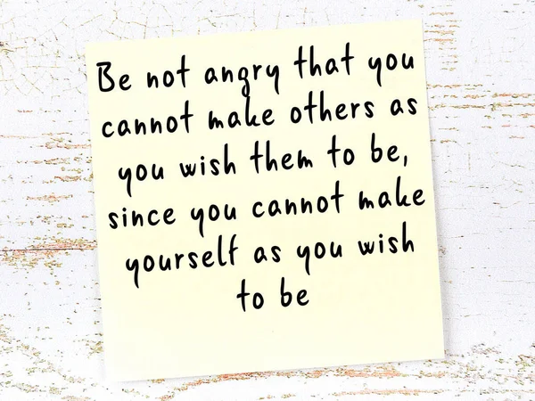 Sarı yapışkan not, ahşap duvarda el yazısıyla yazılmış zekice bir alıntıyla.