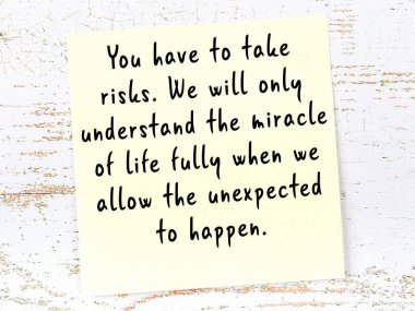 Tahta duvarda asılı sarı yapışkan nota elle yazılmış bilgece bir alıntı.