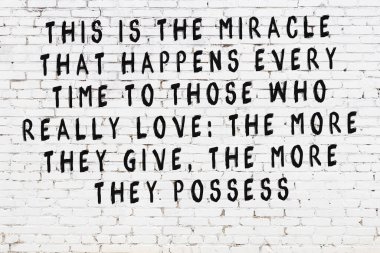 Beyaz tuğla duvara zekice alıntılar yazılı siyah bir yazı.