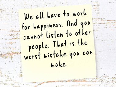 Tahta duvarda el yazısı motivasyon alıntısı olan sarı yapışkan not