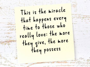 Tahta duvarda asılı sarı yapışkan nota elle yazılmış bilgece bir alıntı.