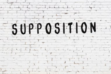 Beyaz tuğlalı duvar. Üzerinde yazı var. El yazısıyla siyah boya.