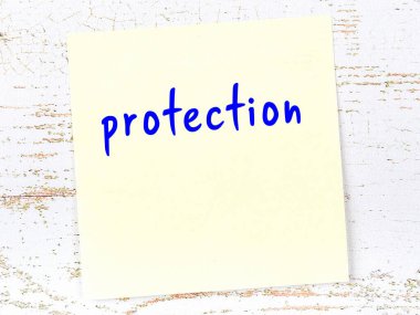 Tahta duvarda el yazısıyla yazması koruması olan sarı yapışkan bir not.