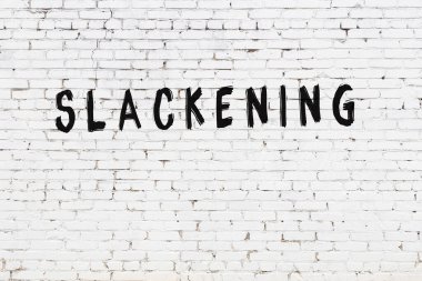 Üzerinde yazı olan beyaz tuğla duvar siyah boyayla el yazısını gevşetiyor.