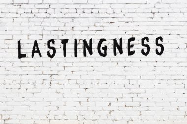 Üzerinde yazı olan beyaz tuğla duvar. Siyah boyayla yazılmış.