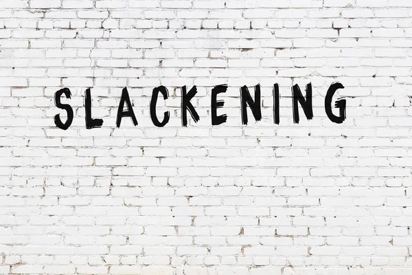 Üzerinde yazı olan beyaz tuğla duvar siyah boyayla el yazısını gevşetiyor.