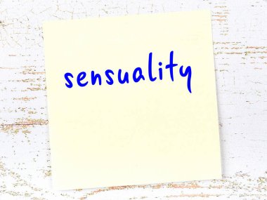 Tahta duvarda el yazısıyla yazılmış şehvet dolu sarı yapışkan bir not.