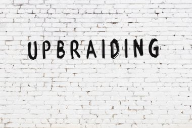 Yazı, beyaz tuğla duvara siyah boya ile yazılmış..