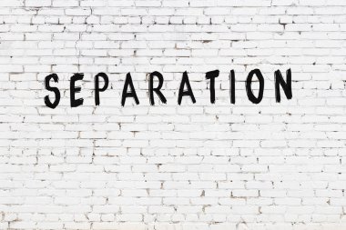 White brick wall with inscription separation handwritten with black paint