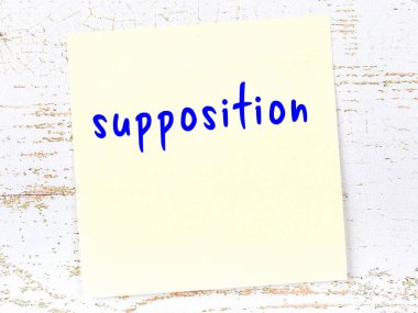 Tahta duvarda el yazısıyla yazılmış sarı yapışkan bir not var.