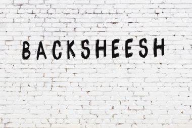 Beyaz tuğlalı duvar. Üzerinde siyah boya ile el yazısı var.