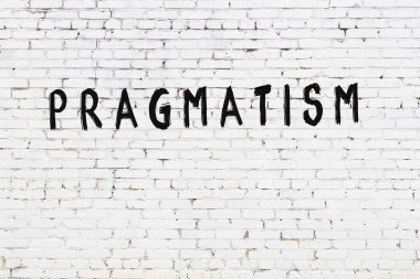 Beyaz tuğladan duvar, siyah boyayla yazılmış pragmatizm.