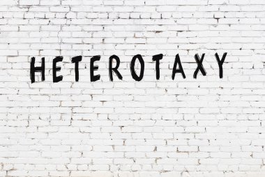 Beyaz tuğla duvara siyah boya ile yazılmış Heterotoksi yazımı.