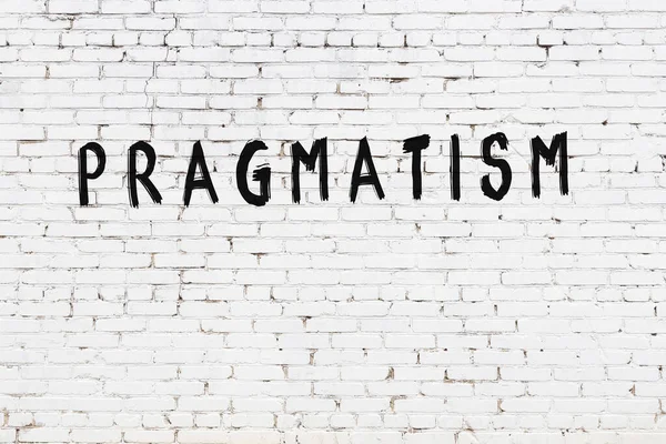 Beyaz tuğladan duvar, siyah boyayla yazılmış pragmatizm.