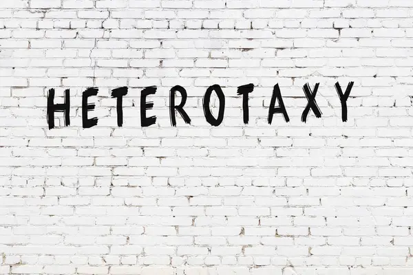 Beyaz tuğla duvara siyah boya ile yazılmış Heterotoksi yazımı.