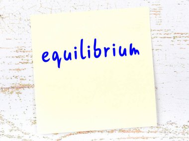 Tahta duvardaki sarı yapışkan notta el yazısıyla yazılmış denge maddesi var.