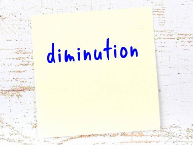 Küçülme hakkında hatırlatma kavramı. Tahta duvarda üzerinde yazı olan sarı yapışkan kağıt.