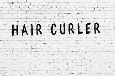 Beyaz tuğla duvara siyah boya ile yazılmış bir saç bigudisi..
