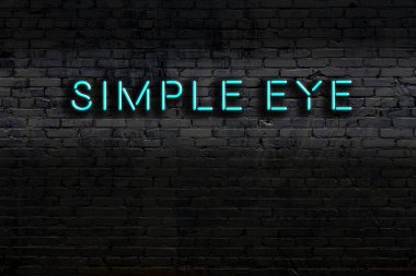 Üzerinde yazı olan neon levhası tuğla duvara yaslanmış basit bir göz. Gece görünümü