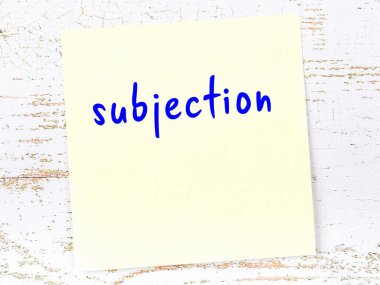 Tahta duvarda el yazısıyla yazılmış sarı yapışkan bir not var.