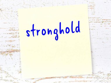 Tahta duvardaki sarı yapışkan notta el yazısıyla yazılmış kaleler var.