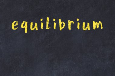 Tebeşir elle yazılmış yazı dengesi siyah masanın üzerinde