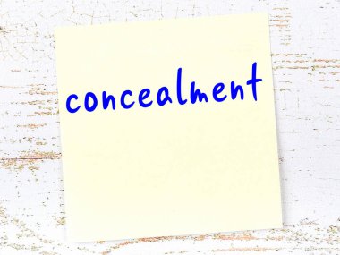 Ahşap duvardaki sarı yapışkan notta el yazısı yazısıyla gizlenmiş.