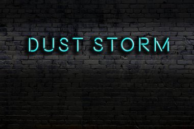 Duvara kazınmış toz fırtınası yazılı neon işareti. Gece görünümü
