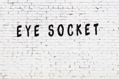 Yazılı beyaz tuğla duvar. Siyah boyayla yazılmış göz yuvası.