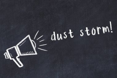 Hoparlörün tebeşir çizimi ve siyah masanın üzerine el yazısıyla yazılmış toz fırtınası.