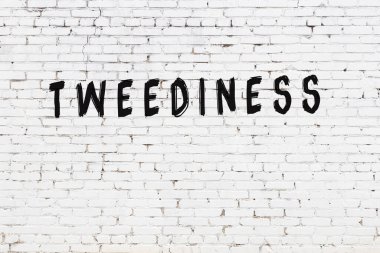 Beyaz tuğlalı duvar, siyah boyalı el yazısıyla yazılmış.