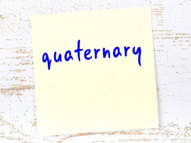 Quaternary hakkında hatırlatma kavramı. Tahta duvarda üzerinde yazı olan sarı yapışkan kağıt.