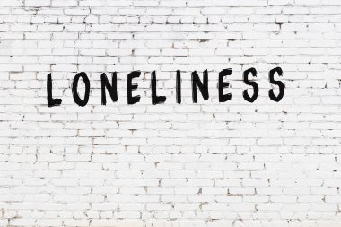 Yazılı beyaz tuğla duvar. Yalnızlık. Siyah boyayla yazılmış.