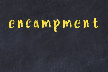 Tebeşir el yazısıyla yazılmış kampı siyah masanın üzerine.