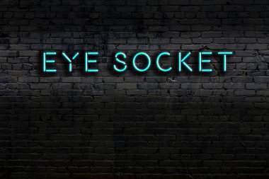 Duvara yazılı bir göz çukuruyla neon levhası. Gece görünümü
