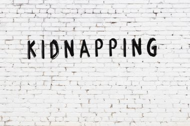 Beyaz tuğlalı duvara siyah boya ile yazılmış bir yazı..