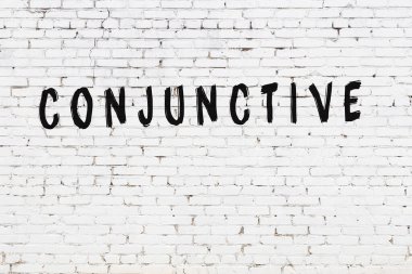 Yazı, beyaz tuğla duvara siyah boya ile yazılmış..