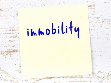 Hareketsizliği hatırlatma kavramı. Tahta duvarda üzerinde yazı olan sarı yapışkan kağıt.