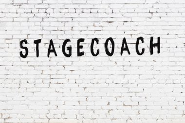 Üzerinde siyah boya ile el yazısı olan beyaz tuğla bir duvar.