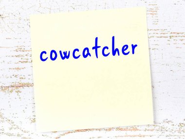 Tahta duvardaki sarı yapışkan notta el yazısıyla yazılmış inek yakalayıcı var.