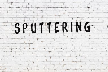 Üzerinde yazı olan beyaz tuğla duvar siyah boyayla el yazısıyla yazılmış.