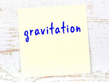 Tahta duvardaki sarı yapışkan notta el yazısıyla yazılmış yerçekimi