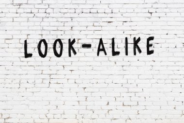 Üzerinde siyah boya bulunan beyaz tuğla bir duvar.