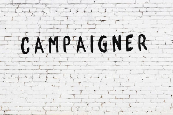 Beyaz tuğla duvara siyah boya ile yazılmış bir yazıt kampanyacısı..