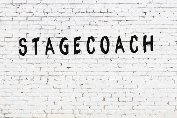 Üzerinde siyah boya ile el yazısı olan beyaz tuğla bir duvar.