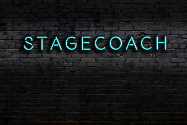Neon sign on brick wall at night. Inscription stagecoach