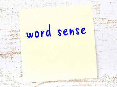 Tahta duvardaki sarı yapışkan notta el yazısıyla yazılmış kelime anlamı var.